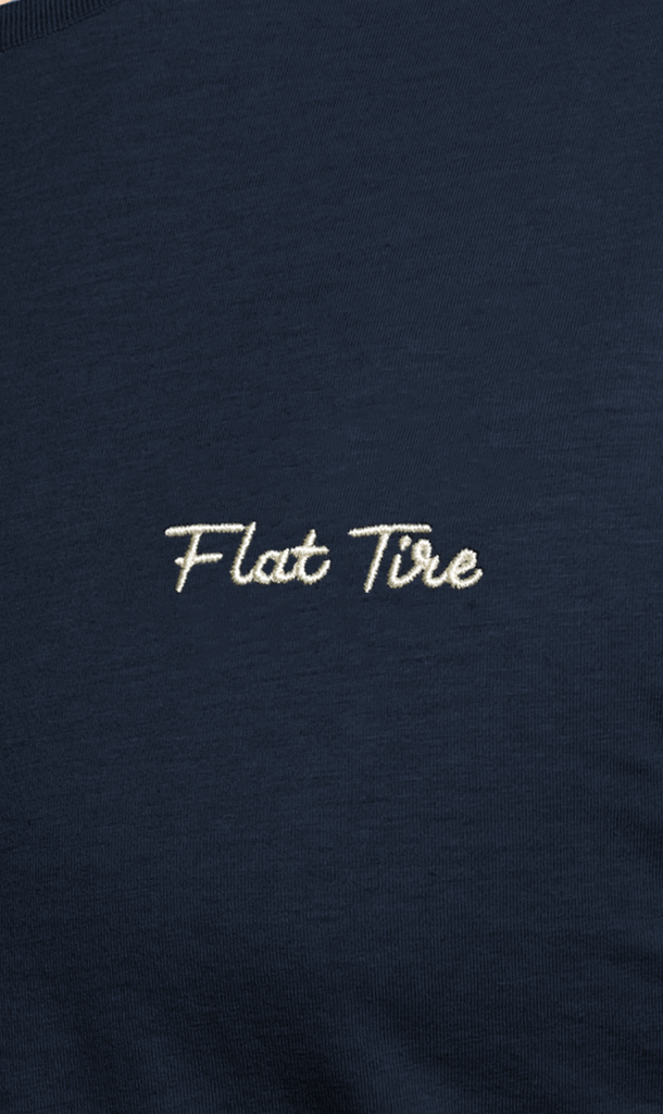 Navy blue shirt with 'Flat Tire' embroidered in white on a dark background